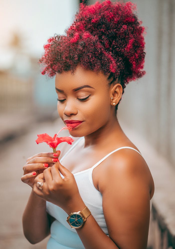 Beautiful woman with colorful hair holding a flower, exuding elegance and fashion outdoors.